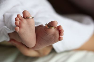 Low section of baby with wedding rings on toes