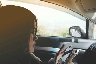 Woman using smart phone while travelling in car