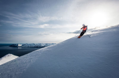 A man skiing downhill with ocean in the background in iceland