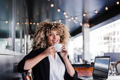 Beautiful hispanic afro business woman in cafe working on laptop and mobile phone.business and tech