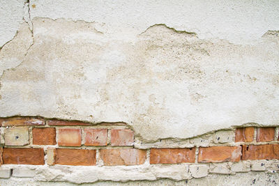 Broken vintage bricklaying wall fragment. old red clay bricks and plaster frame background texture