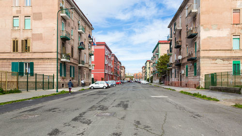 Empty road amidst buildings in city against sky