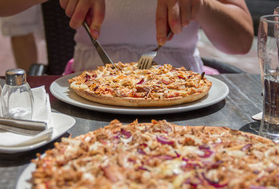 Midsection of woman eating pizza in restaurant