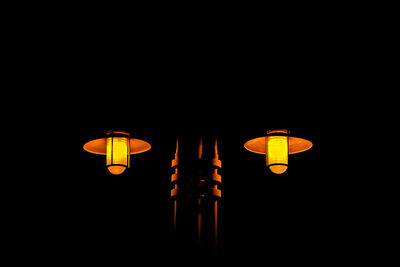 Low angle view of illuminated lanterns over black background