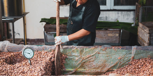 Midsection of man working with cocoa seeds at factory