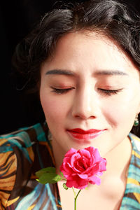 Close-up of woman with eyes closed smelling pink rose