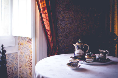 Close-up of kettle with tea cups on table at home