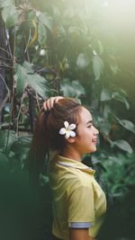 Portrait of smiling young woman standing against plants