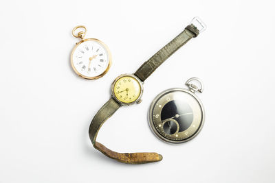 Directly above shot of pocket watches and wristwatch against white background