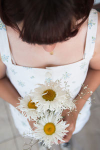 Midsection of woman holding white flowering plant