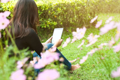 Woman using phone while sitting on grass