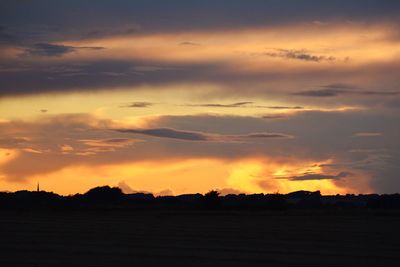Scenic view of dramatic sky over silhouette landscape during sunset