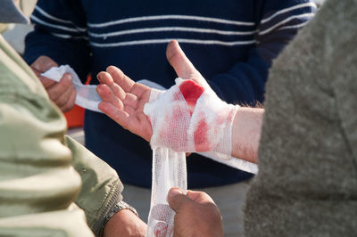 Midsection of man wrapping bandage on hand