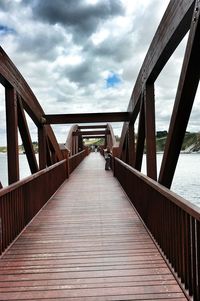 Bridge over river against cloudy sky