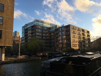 Buildings by river against sky in city