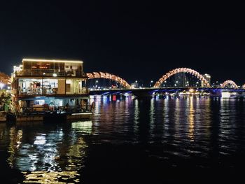 Illuminated bridge over river against sky at night