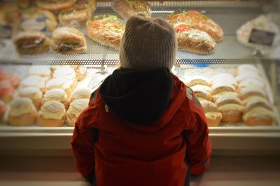 Rear view of girl looking towards food in display cabinet