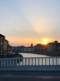 River by buildings against sky during sunset