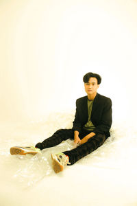 Portrait of young man sitting against white background