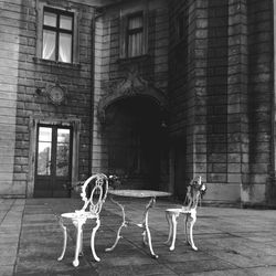 Chairs and table on walkway against building