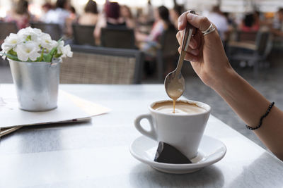 Cropped image of woman stirring coffee on table