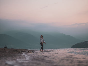 Woman standing on mountain against sky during sunset