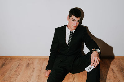 Man with card sitting on floor against wall