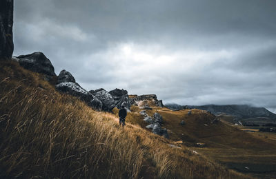 Man climbing on mountain against sky