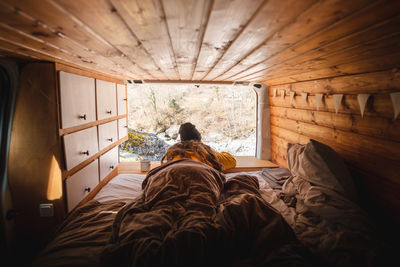 Rear view of man sitting on bed