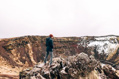 Rear view of man standing on rock against sky