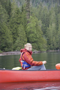 Portrait of smiling woman sitting in boat on lake