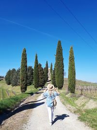 Woman walking on footpath against trees