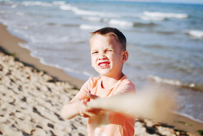 Portrait of smiling boy playing with stick at beach
