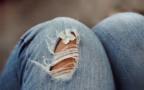 Midsection of person with flower on jeans