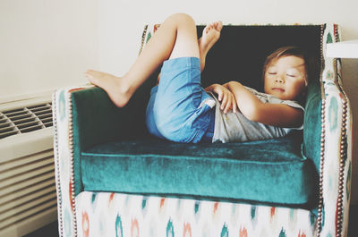 Rear view of girl lying on sofa at home