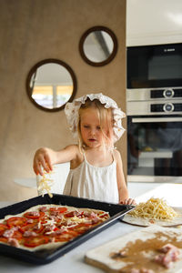 Little girl cooking pizza in the kitchen