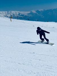 Woman snowboarding on snow covered mountain