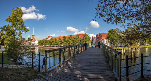 Footpath amidst trees and buildings against sky