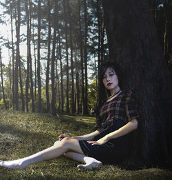 Young woman sitting on tree trunk in forest