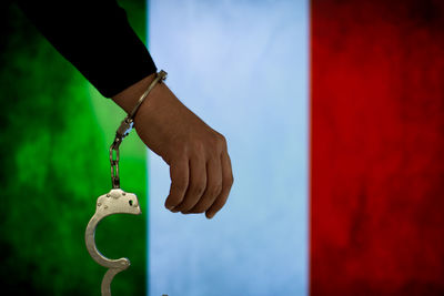 Cropped hand of male criminal with handcuffs against italian flag