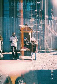 Man with umbrella on street seen through glass window