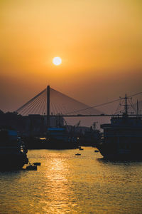 Silhouette bridge over sea against romantic sky at sunset