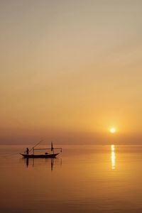 Silhouette boat in sea against sky during sunset