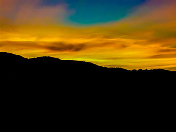 Silhouette landscape against dramatic sky during sunset