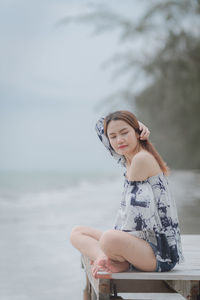 Side view of young woman against sea