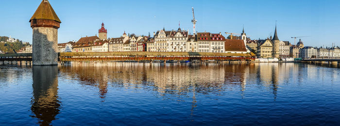 Luzern is reflected on the river on a sunny day with the chapel bridge