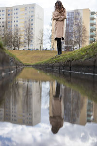 Reflection of woman standing on puddle in city