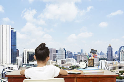 Digital composite image of girl studying against buildings