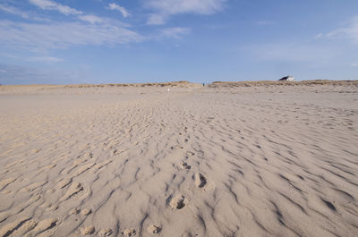 Sand dunes at beach against sky