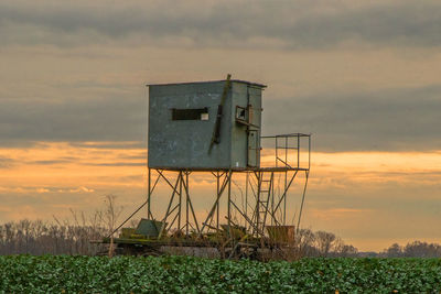 Lifeguard hut on field against sky during sunset